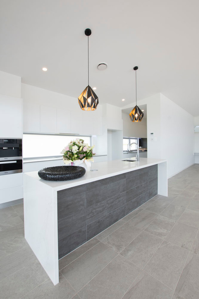 Design ideas for a mid-sized contemporary galley open plan kitchen in Brisbane with an undermount sink, white cabinets, quartz benchtops, black splashback, glass sheet splashback, stainless steel appliances, porcelain floors and with island.