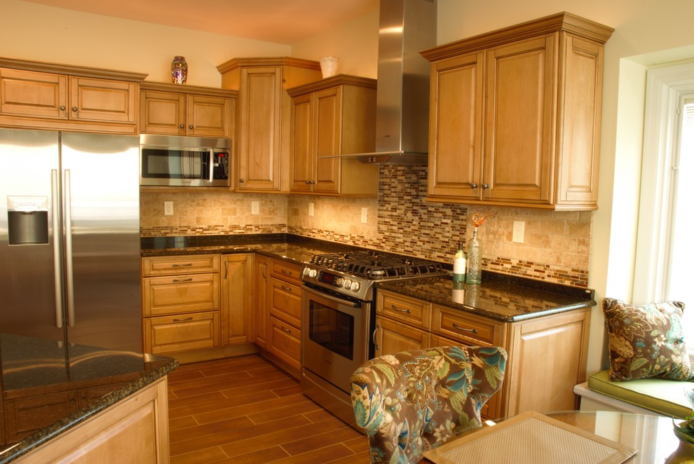 Example of a mid-sized transitional l-shaped ceramic tile eat-in kitchen design with a farmhouse sink, raised-panel cabinets, medium tone wood cabinets, granite countertops, beige backsplash, ceramic backsplash, stainless steel appliances and an island