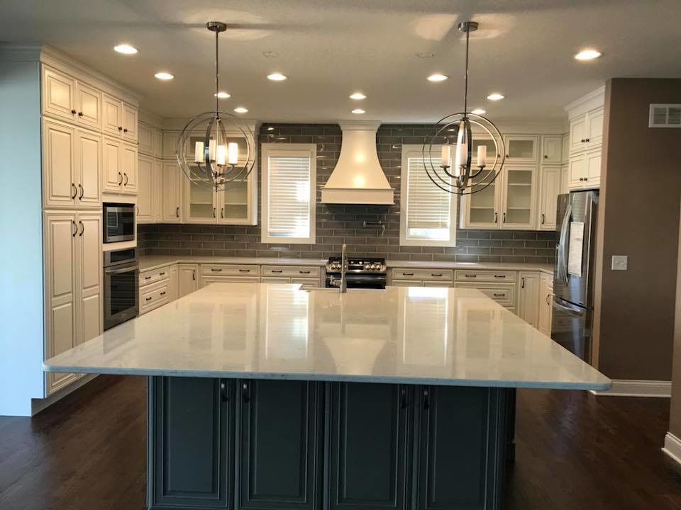 Mid-sized transitional u-shaped medium tone wood floor and brown floor open concept kitchen photo in Cincinnati with a farmhouse sink, glass-front cabinets, white cabinets, quartz countertops, gray backsplash, subway tile backsplash, stainless steel appliances, an island and white countertops