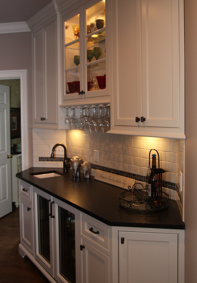 This is an example of a small transitional single-wall wet bar in Cleveland with an undermount sink, beaded inset cabinets, white cabinets, quartz benchtops, white splashback, ceramic splashback and medium hardwood floors.