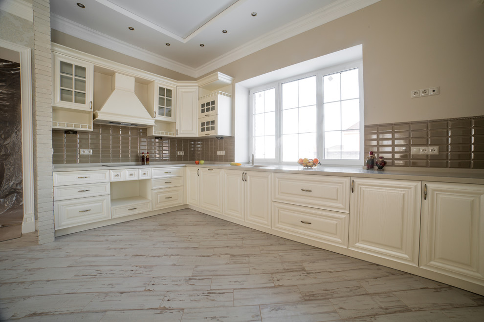 Inspiration for a large country u-shaped eat-in kitchen in Moscow with an undermount sink, raised-panel cabinets, beige cabinets, solid surface benchtops, brown splashback, ceramic splashback, white appliances, ceramic floors, no island, beige floor and beige benchtop.