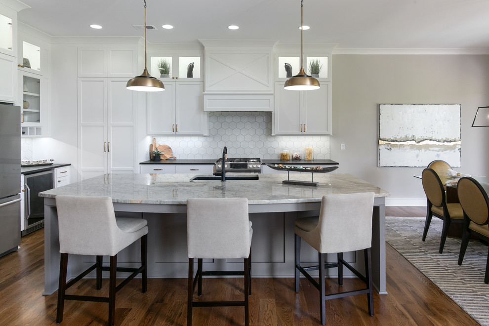 This is an example of a country eat-in kitchen in Kansas City with an undermount sink, shaker cabinets, white cabinets, white splashback, stainless steel appliances, dark hardwood floors, with island, brown floor and black benchtop.