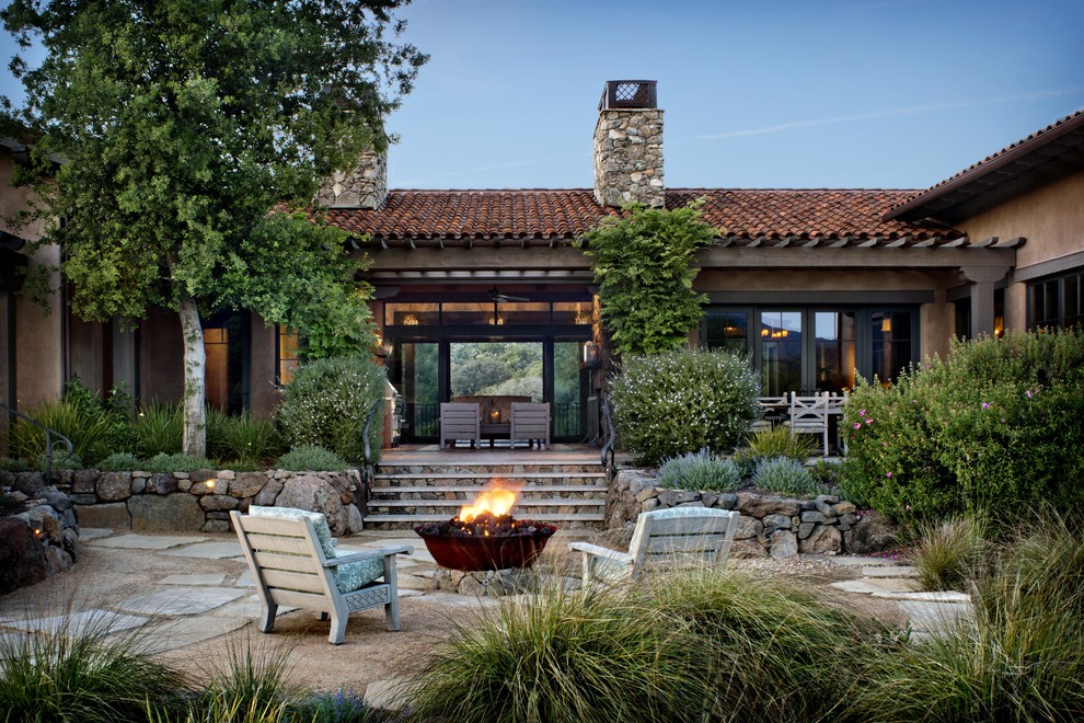 Mediterranean patio in Denver with a fire feature, natural stone pavers and no cover.
