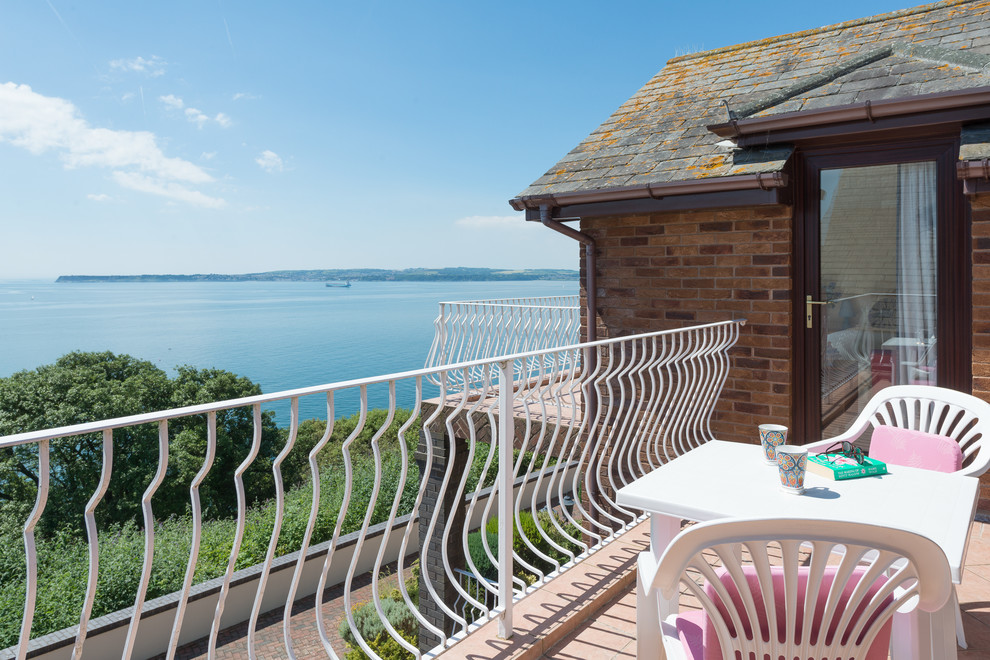 This is an example of a medium sized traditional front patio in Devon with a water feature and tiled flooring.