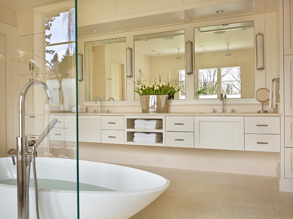 This is an example of a large transitional master bathroom in Seattle with an undermount sink, marble benchtops, a freestanding tub, an open shower, beige tile, beige walls and limestone floors.