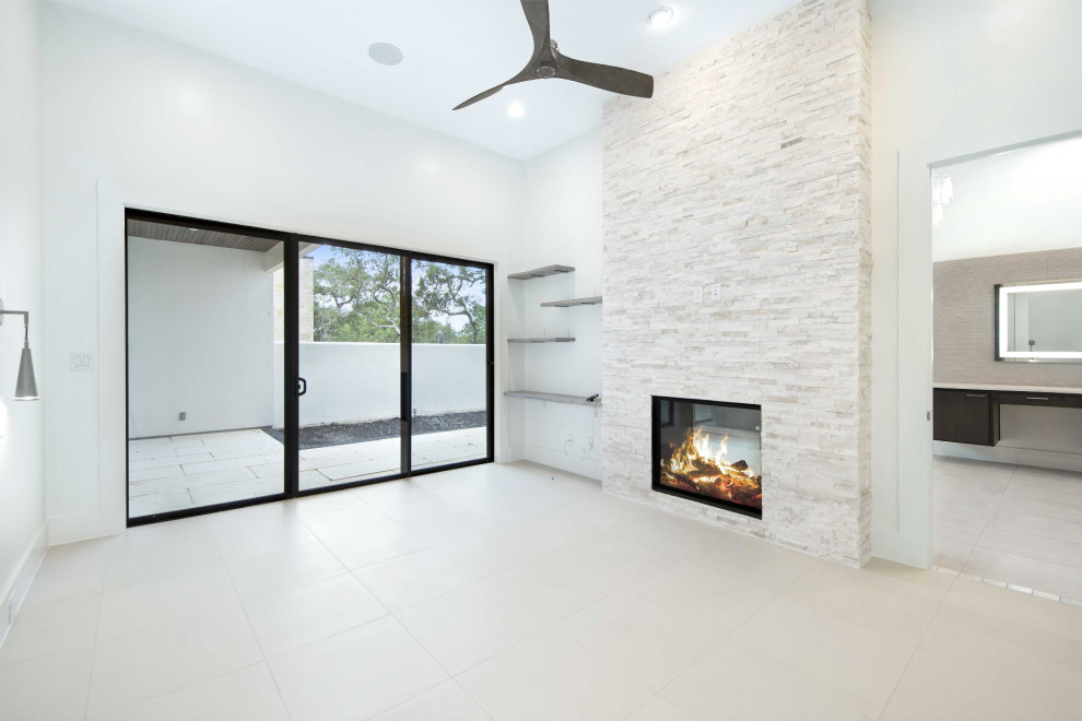 This is an example of a mid-sized transitional master bedroom in Austin with white walls, porcelain floors, a two-sided fireplace, a tile fireplace surround and white floor.