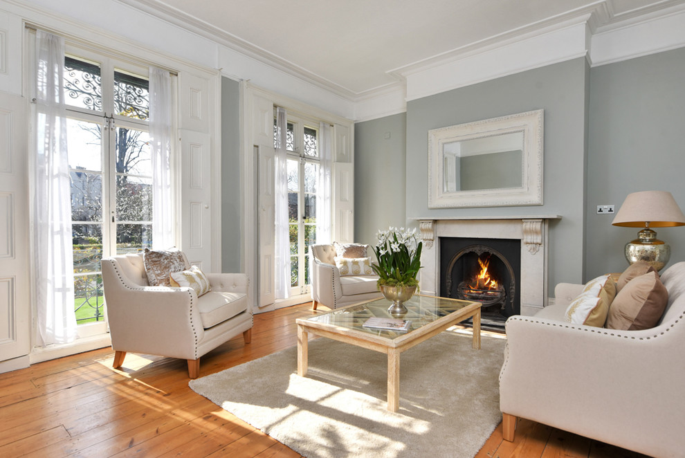 Photo of a mid-sized traditional formal enclosed living room in Other with grey walls, medium hardwood floors, a standard fireplace and brown floor.