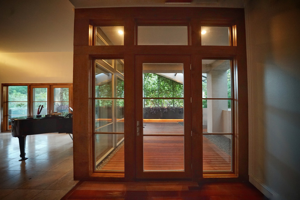 Idée de décoration pour une porte d'entrée minimaliste de taille moyenne avec un mur gris, parquet foncé, une porte simple, une porte en bois foncé, un sol marron, un plafond à caissons et du lambris.