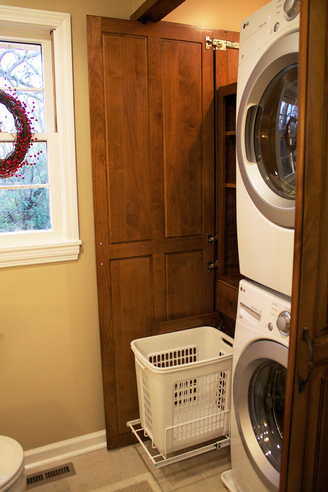 This is an example of a small arts and crafts laundry room in Other with medium wood cabinets, brown walls and travertine floors.
