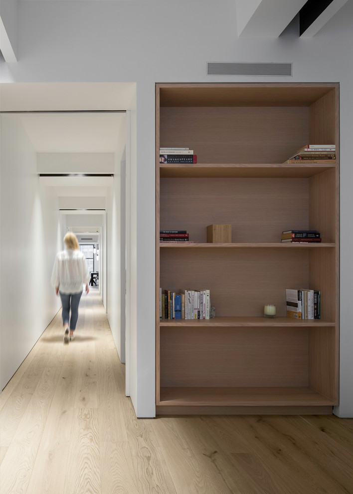 Large contemporary hallway in New York with white walls, light hardwood floors and beige floor.