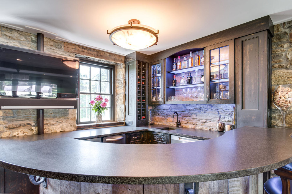 This is an example of a large country l-shaped seated home bar in DC Metro with a drop-in sink, beaded inset cabinets, distressed cabinets, granite benchtops and medium hardwood floors.