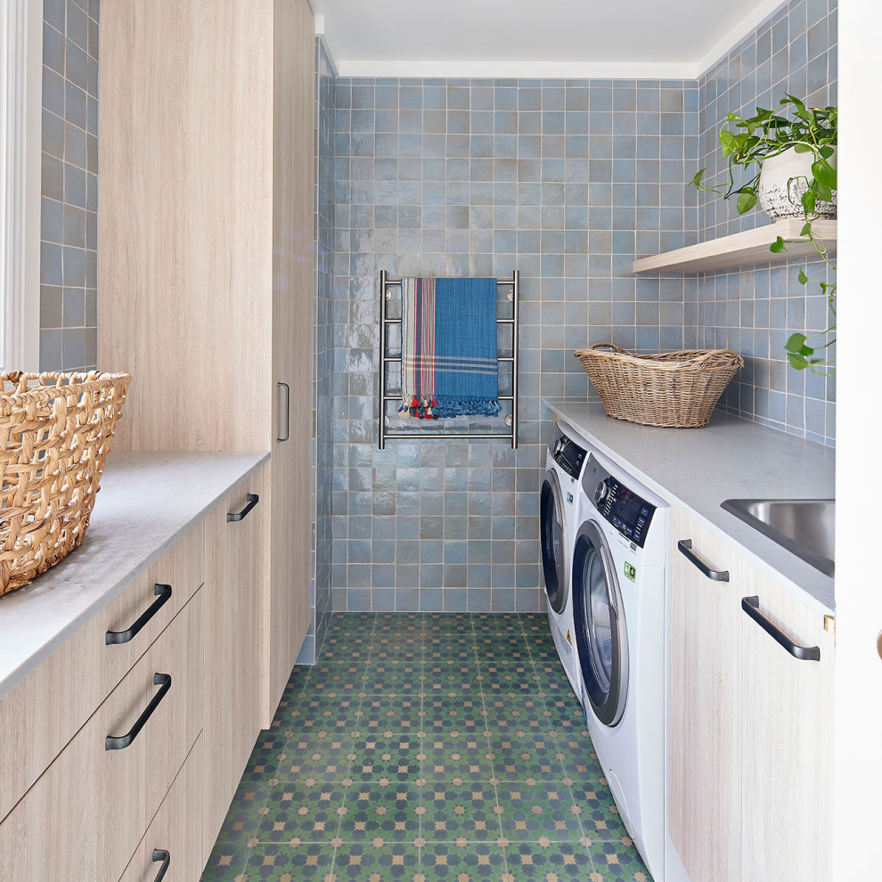 Design ideas for a mid-sized beach style galley utility room in Central Coast with a drop-in sink, light wood cabinets, marble benchtops, multi-coloured walls, a side-by-side washer and dryer, multi-coloured floor and white benchtop.