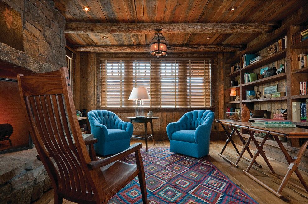 Example of a mountain style freestanding desk medium tone wood floor home office design with a stone fireplace