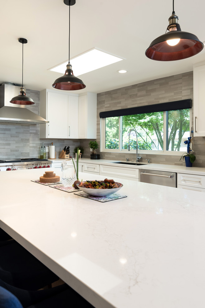 Mid-sized transitional l-shaped eat-in kitchen in San Francisco with an undermount sink, shaker cabinets, white cabinets, marble benchtops, grey splashback, ceramic splashback, stainless steel appliances, light hardwood floors, with island and beige floor.