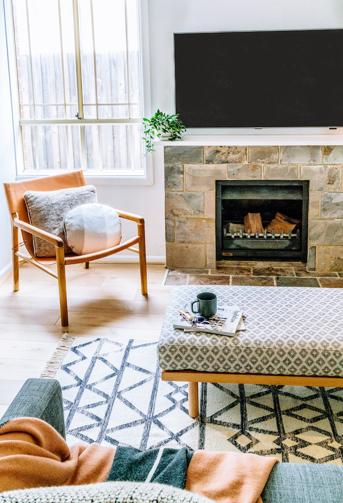 Inspiration for a small transitional open concept living room in Melbourne with white walls, light hardwood floors, a standard fireplace, a stone fireplace surround and a wall-mounted tv.