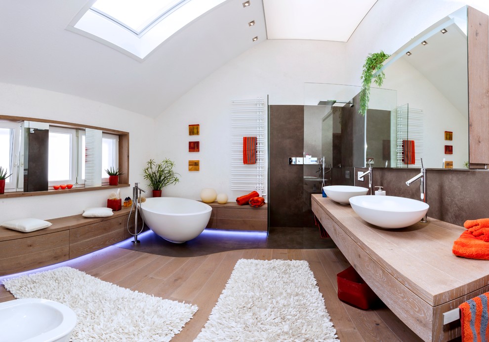 This is an example of a large contemporary master bathroom in Stuttgart with white walls, a vessel sink, wood benchtops, medium hardwood floors, an open shower, flat-panel cabinets, brown cabinets, a corner tub, an open shower, a wall-mount toilet, brown tile, brown floor and brown benchtops.