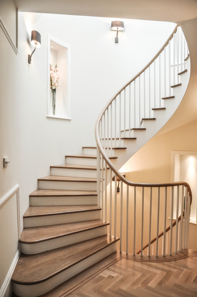 This is an example of a traditional wood curved staircase in London with painted wood risers.