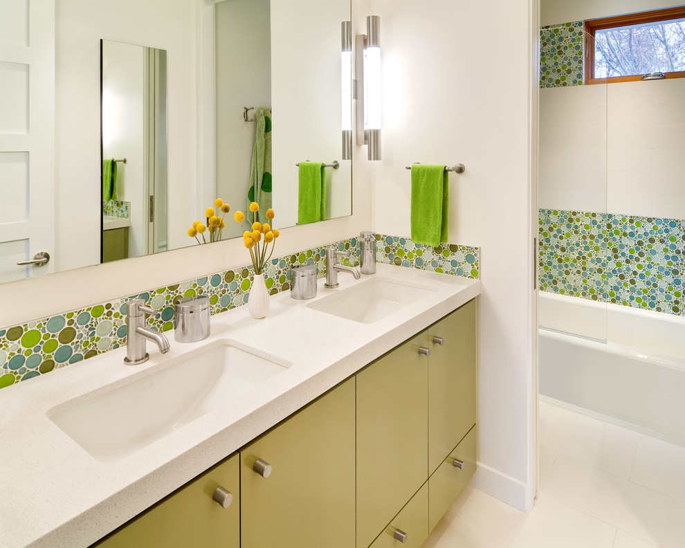 This is an example of a contemporary kids bathroom in San Francisco with an undermount sink, flat-panel cabinets, green cabinets, an alcove tub, a shower/bathtub combo, multi-coloured tile and mosaic tile.