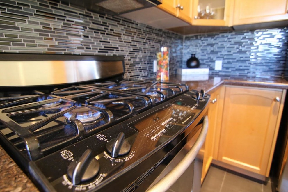 Example of a mid-sized transitional l-shaped porcelain tile eat-in kitchen design in Toronto with an undermount sink, recessed-panel cabinets, light wood cabinets, granite countertops, multicolored backsplash, matchstick tile backsplash, stainless steel appliances and a peninsula
