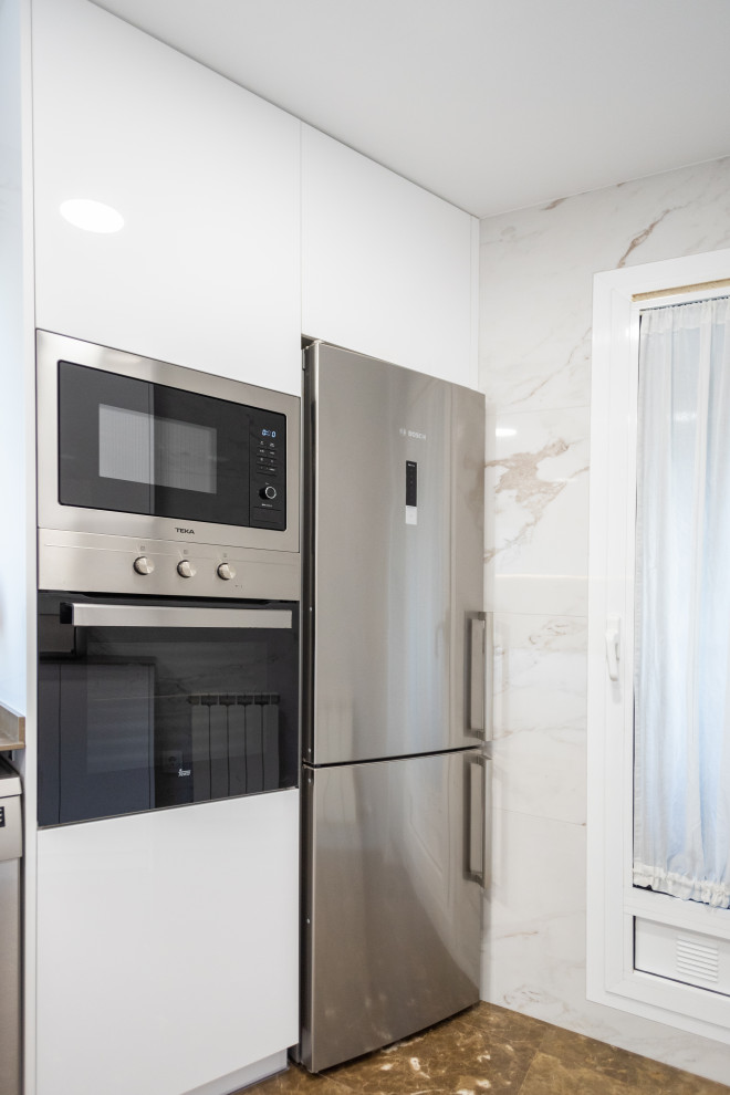 Foto på ett avskilt, stort funkis grå l-kök, med en enkel diskho, släta luckor, vita skåp, vitt stänkskydd, stänkskydd i keramik, rostfria vitvaror, terrazzogolv och brunt golv