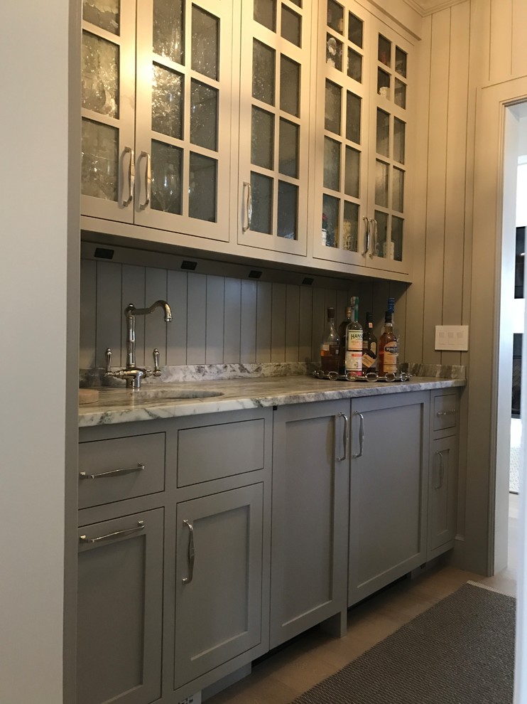 This is an example of a mid-sized transitional single-wall wet bar in Boston with an undermount sink, shaker cabinets, grey cabinets, granite benchtops, grey splashback, timber splashback, medium hardwood floors, brown floor and grey benchtop.