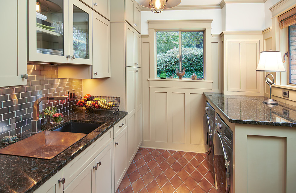 This is an example of a small arts and crafts galley utility room in Cleveland with a single-bowl sink, recessed-panel cabinets, granite benchtops, a side-by-side washer and dryer, beige cabinets, white walls, terra-cotta floors and orange floor.