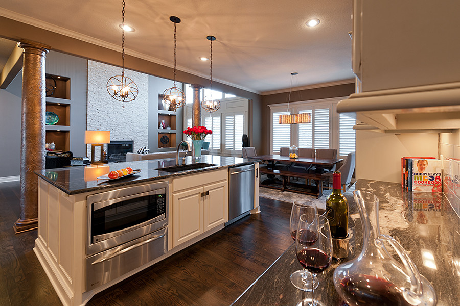 Design ideas for a large transitional u-shaped open plan kitchen in Kansas City with an undermount sink, white cabinets, granite benchtops, white splashback, subway tile splashback, stainless steel appliances, dark hardwood floors, with island and brown floor.