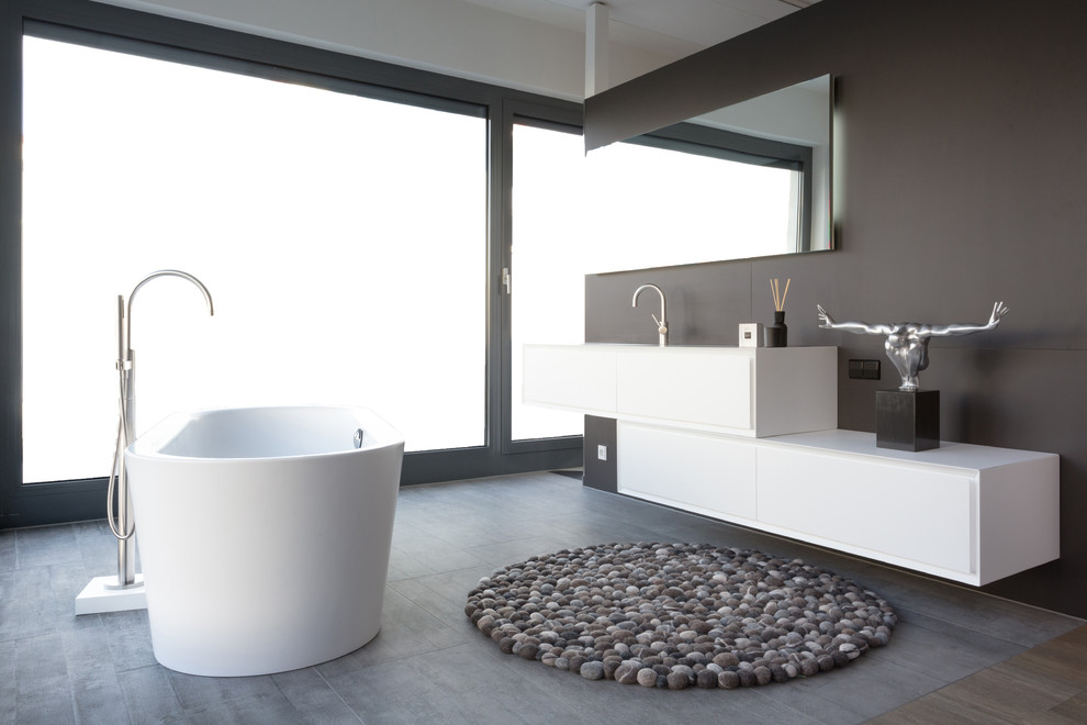 This is an example of a small contemporary master bathroom in Other with flat-panel cabinets, white cabinets, a freestanding tub, brown tile, an integrated sink, concrete benchtops, grey floor and white benchtops.