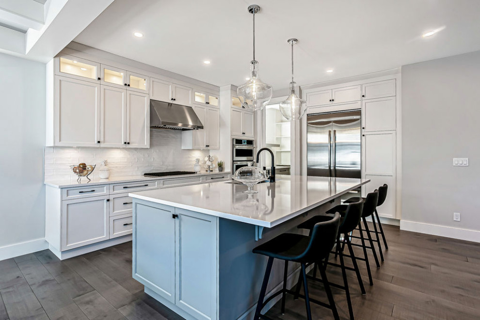 Transitional l-shaped light wood floor and gray floor eat-in kitchen photo in Calgary with a double-bowl sink, shaker cabinets, gray cabinets, quartz countertops, white backsplash, ceramic backsplash, stainless steel appliances, an island and white countertops