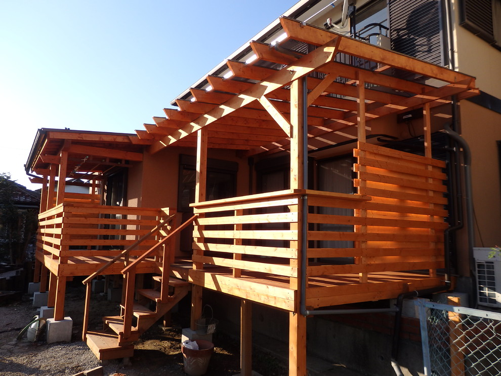 This is an example of an asian backyard deck in Other with a pergola.