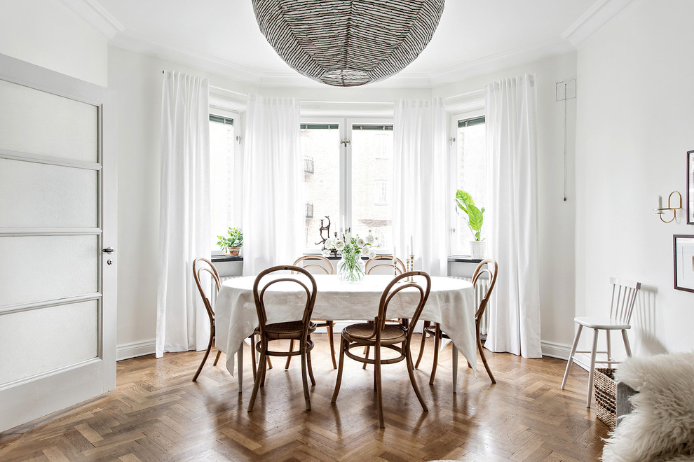 Scandinavian open plan dining in Gothenburg with white walls, beige floor and light hardwood floors.