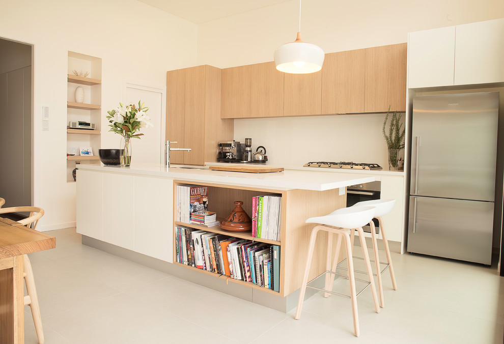 Photo of a mid-sized scandinavian galley open plan kitchen in Melbourne with an undermount sink, flat-panel cabinets, white cabinets, quartz benchtops, stone slab splashback, stainless steel appliances, porcelain floors and with island.