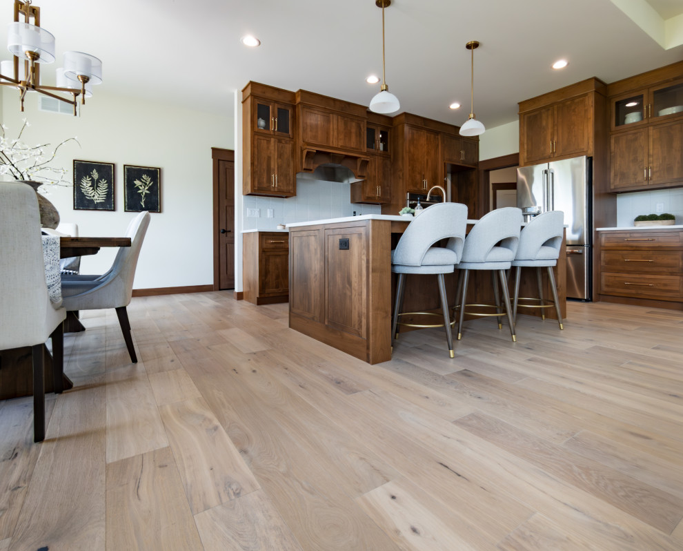 Example of a transitional galley light wood floor and beige floor eat-in kitchen design with an undermount sink, shaker cabinets, medium tone wood cabinets, quartz countertops, white backsplash, ceramic backsplash, an island and white countertops