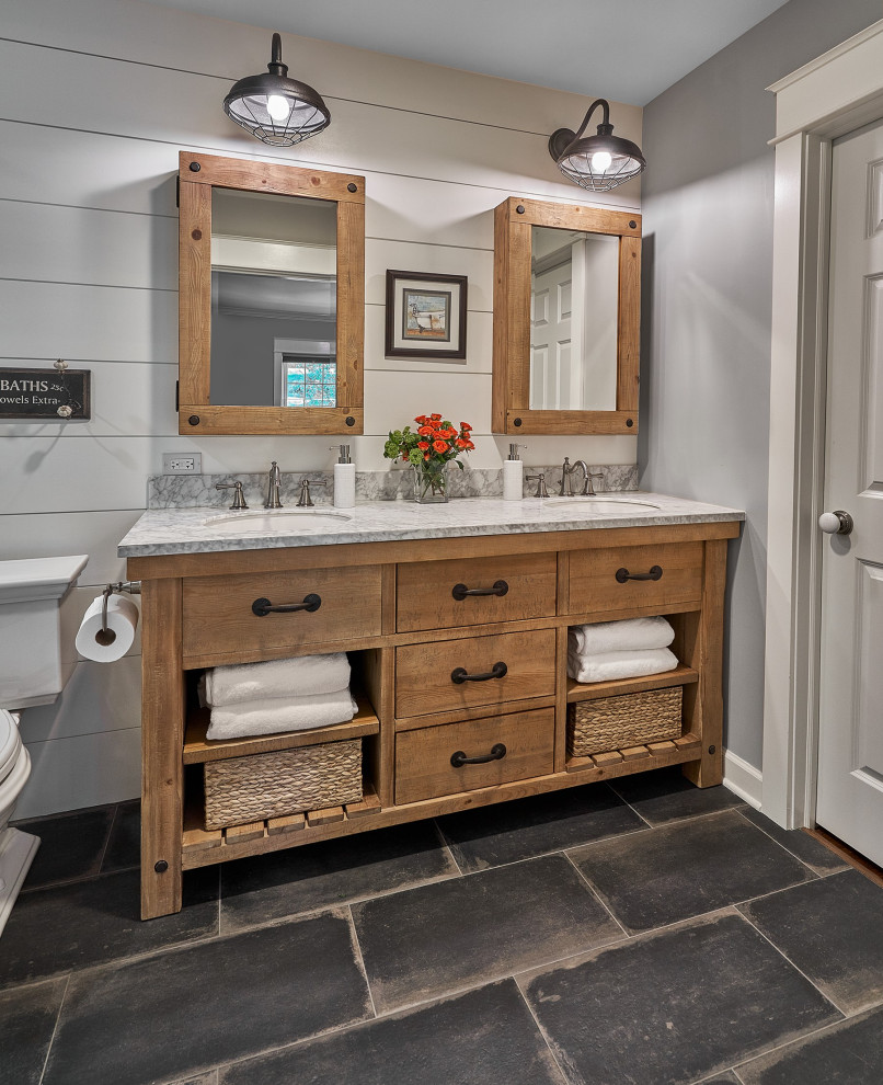 Photo of a mid-sized country 3/4 bathroom in Chicago with distressed cabinets, marble benchtops, white benchtops, a freestanding vanity, grey walls, porcelain floors, black floor, a double vanity, planked wall panelling, an enclosed toilet and flat-panel cabinets.