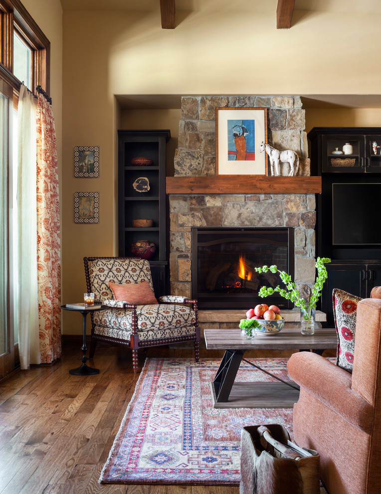 Design ideas for a family room in Denver with yellow walls, light hardwood floors, a standard fireplace, a stone fireplace surround and brown floor.
