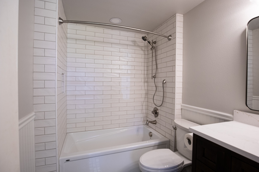 Exemple d'une petite salle de bain principale nature avec un placard à porte shaker, des portes de placard marrons, une baignoire en alcôve, un combiné douche/baignoire, WC à poser, un carrelage blanc, des carreaux de céramique, un mur gris, un sol en carrelage de céramique, un lavabo encastré, un plan de toilette en quartz modifié, un sol gris, une cabine de douche avec un rideau, un plan de toilette blanc, une niche, meuble simple vasque, meuble-lavabo sur pied et boiseries.