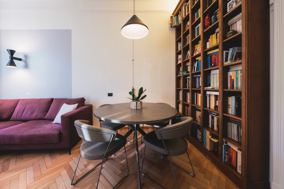 Imagen de sala de estar con biblioteca cerrada ecléctica de tamaño medio con paredes grises, suelo de madera clara, televisor independiente y suelo beige