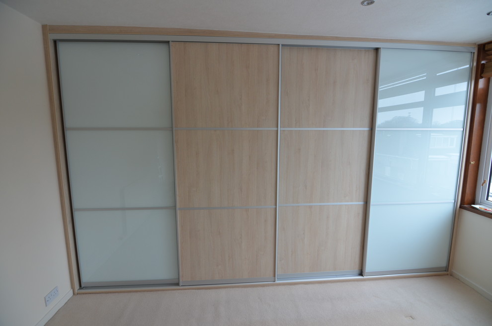 Inspiration for a large modern built-in wardrobe with glass-front cabinets and light wood cabinets.
