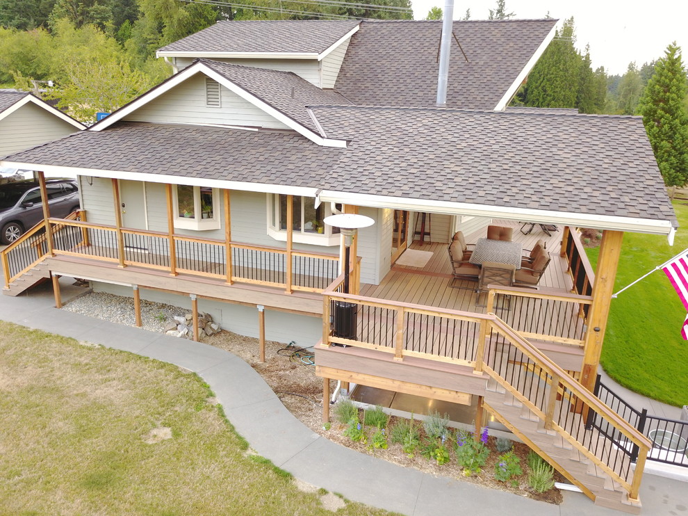 Large country backyard deck in Seattle with a roof extension and an outdoor kitchen.