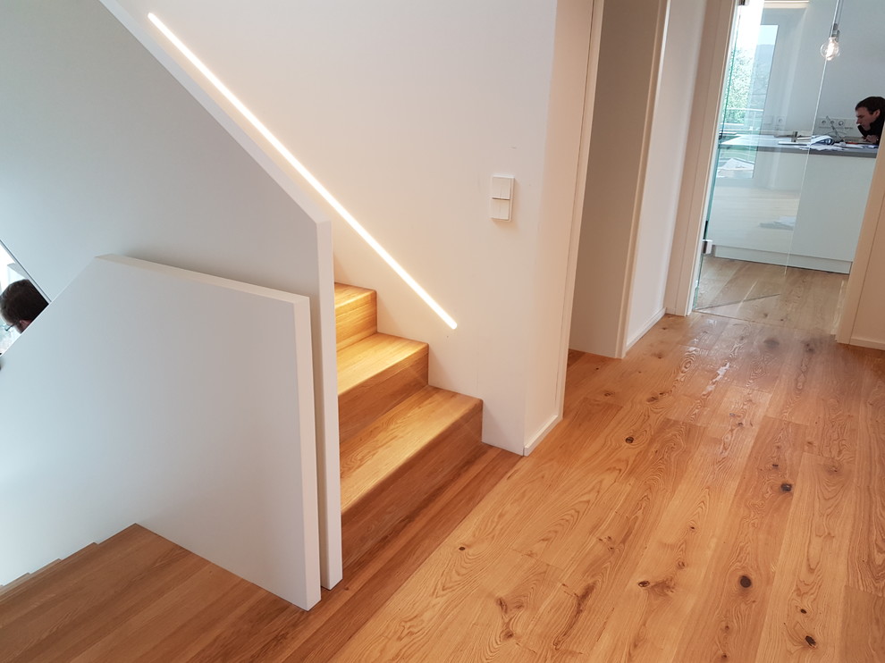 Imagen de escalera en U contemporánea grande con escalones de madera, contrahuellas de madera y barandilla de madera
