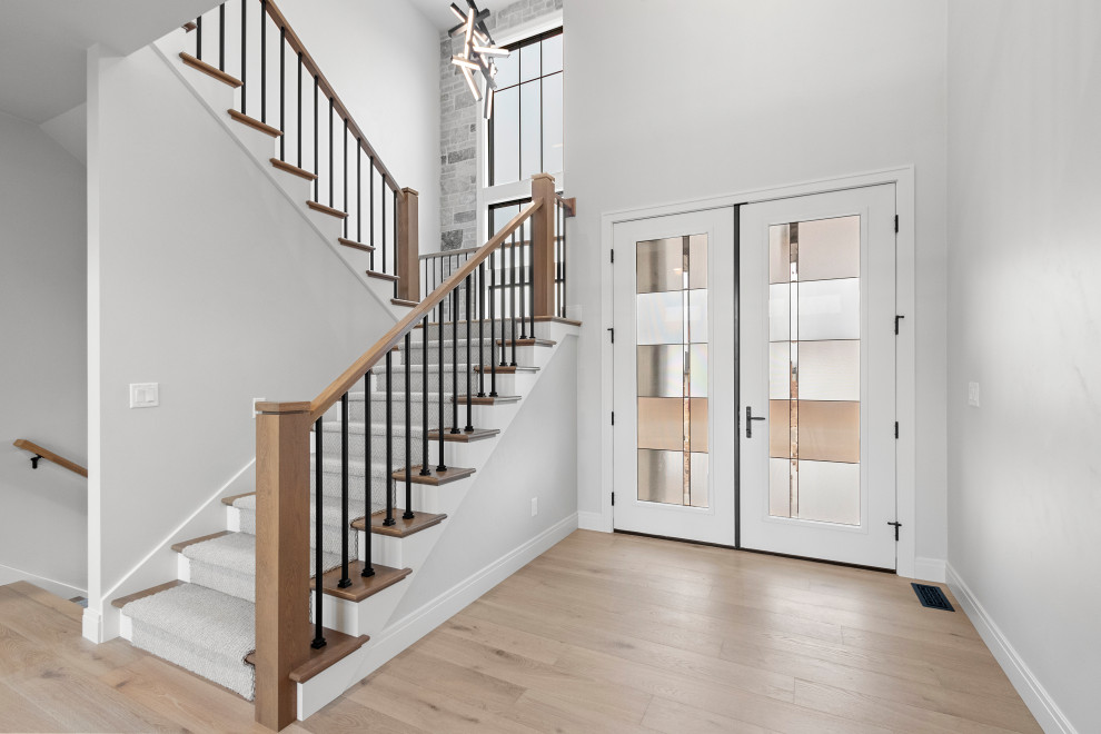 Example of a large transitional light wood floor and brown floor foyer design with white walls and a white front door