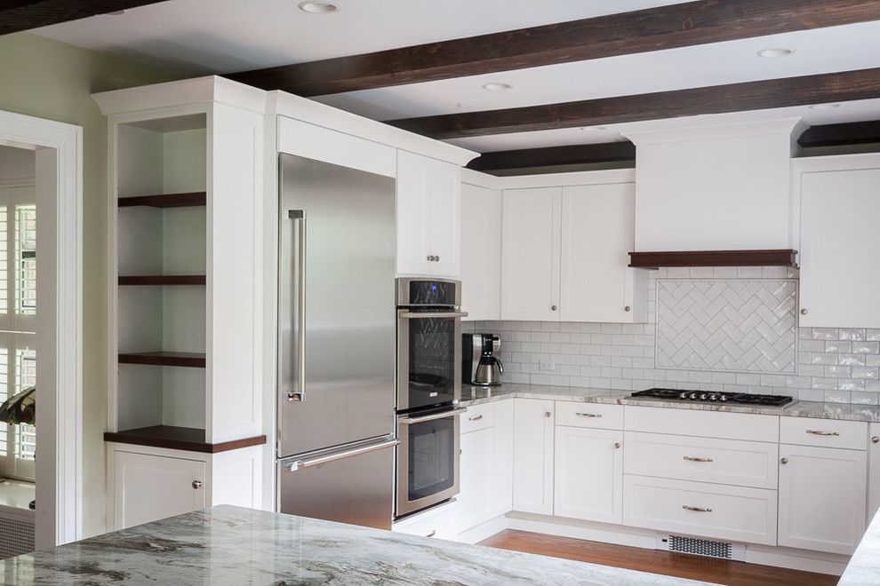 Mid-sized transitional u-shaped medium tone wood floor enclosed kitchen photo with an undermount sink, shaker cabinets, white cabinets, quartzite countertops, white backsplash, subway tile backsplash, stainless steel appliances and a peninsula