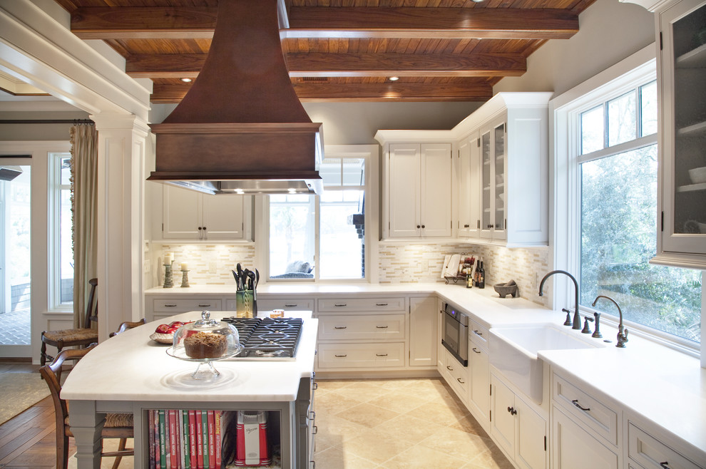 Photo of a mid-sized traditional u-shaped eat-in kitchen in Charleston with shaker cabinets, a farmhouse sink, white cabinets, marble benchtops, beige splashback, matchstick tile splashback, stainless steel appliances, limestone floors and with island.