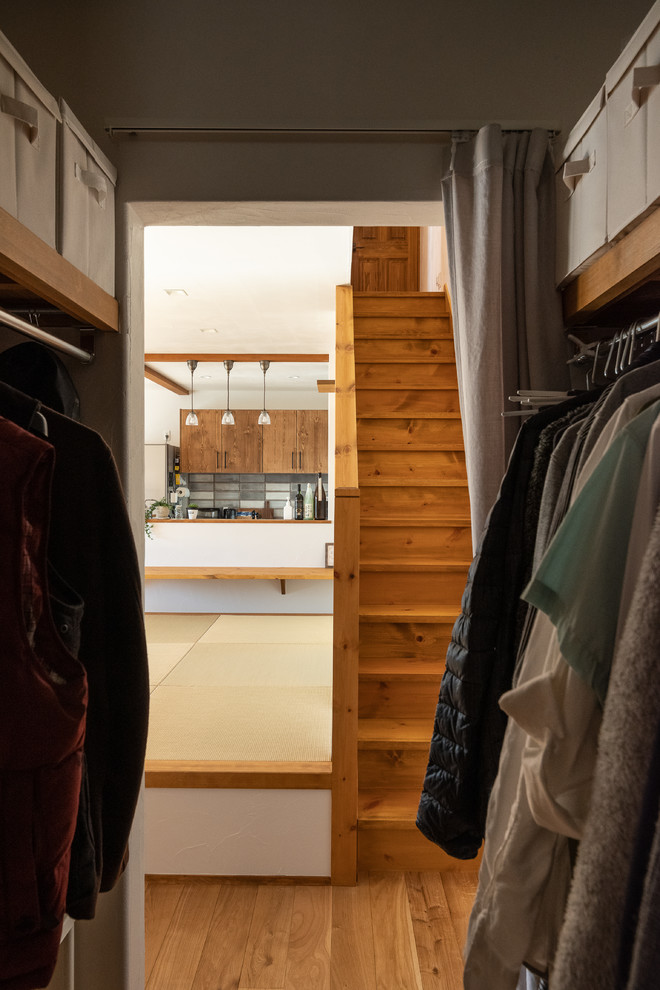 This is an example of a world-inspired gender neutral walk-in wardrobe in Other with open cabinets, medium hardwood flooring and multi-coloured floors.