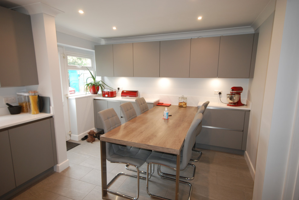 Design ideas for a mid-sized contemporary l-shaped eat-in kitchen in Surrey with an undermount sink, flat-panel cabinets, grey cabinets, solid surface benchtops, red splashback, timber splashback, black appliances, porcelain floors, no island, grey floor and white benchtop.