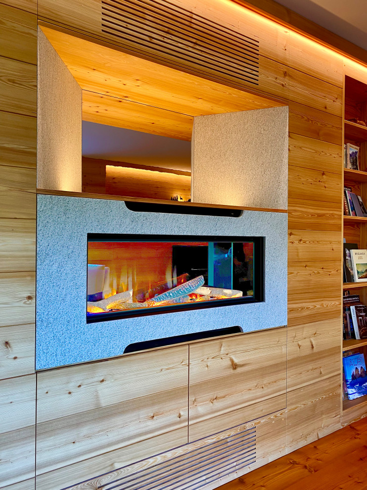 Cette photo montre un salon scandinave en bois de taille moyenne et fermé avec une bibliothèque ou un coin lecture, un sol en bois brun, une cheminée, un manteau de cheminée en pierre et aucun téléviseur.