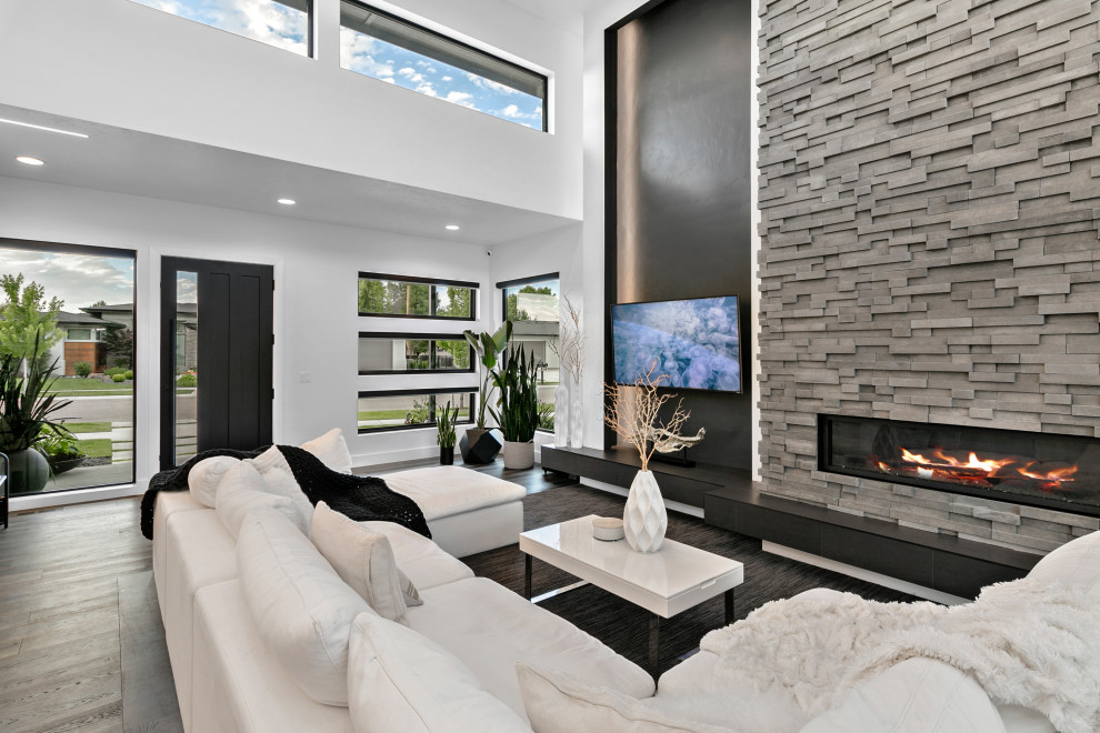 Expansive modern formal open concept living room in Boise with white walls, vaulted, medium hardwood floors, beige floor, a wall-mounted tv and panelled walls.