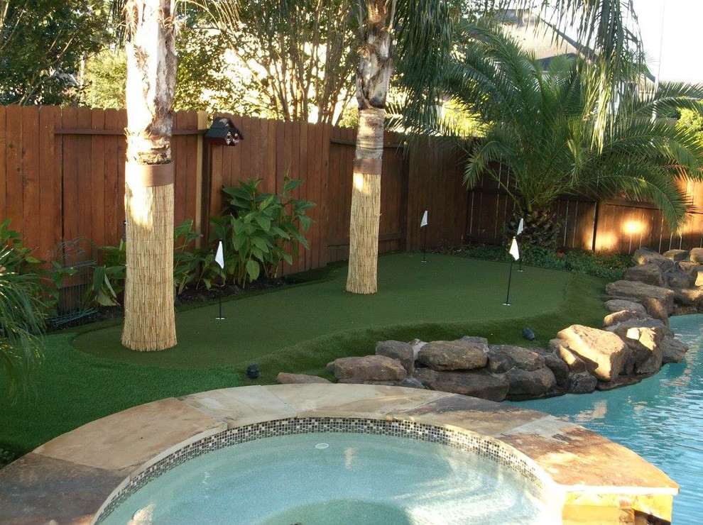 Design ideas for a mid-sized tropical backyard garden in Houston with a water feature and natural stone pavers.