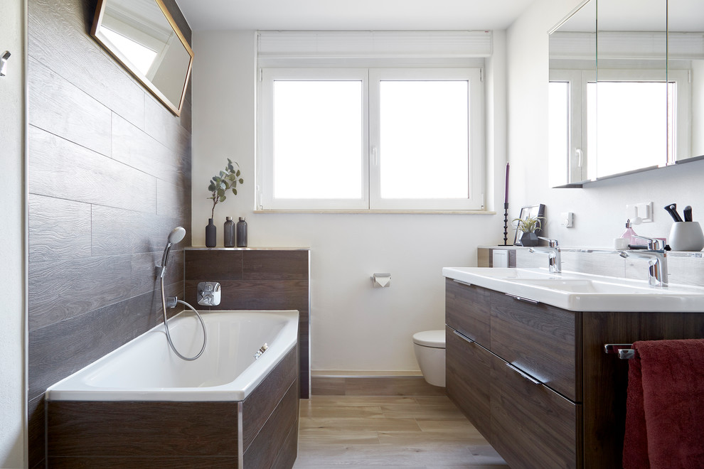 Photo of a medium sized contemporary family bathroom in Berlin with flat-panel cabinets, dark wood cabinets, a corner bath, a corner shower, brown tiles, ceramic tiles, laminate floors, a built-in sink, laminate worktops, a hinged door, white worktops, double sinks, a floating vanity unit and a wall mounted toilet.