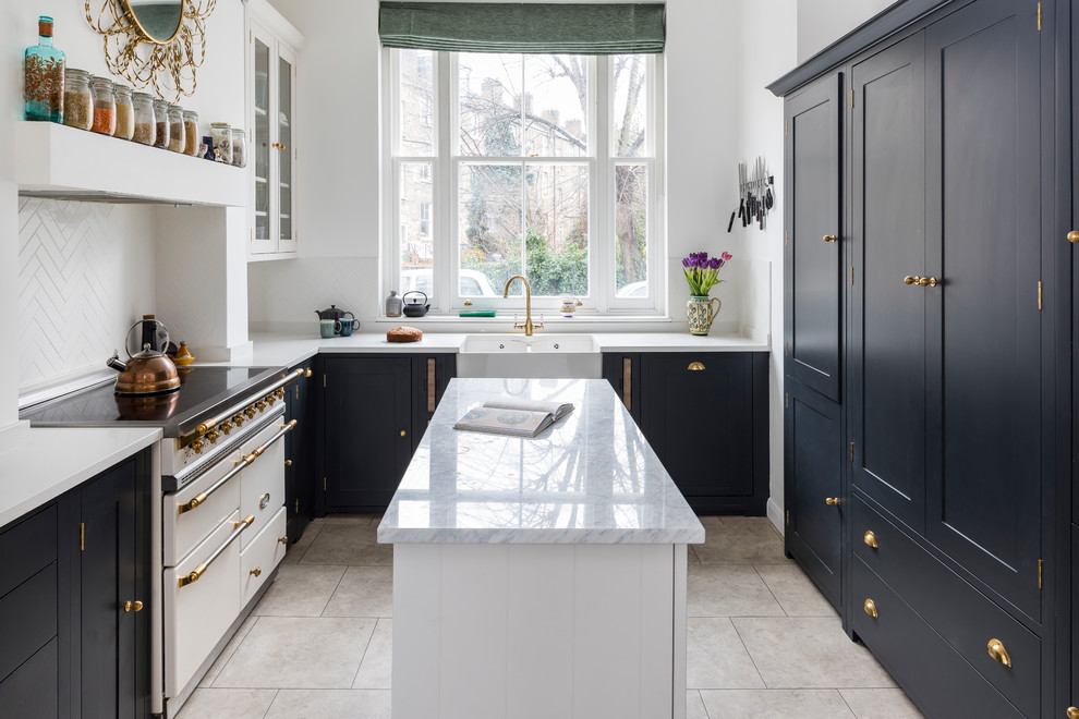 Small transitional l-shaped eat-in kitchen in London with a farmhouse sink, shaker cabinets, black cabinets, quartzite benchtops, limestone floors, with island and beige floor.